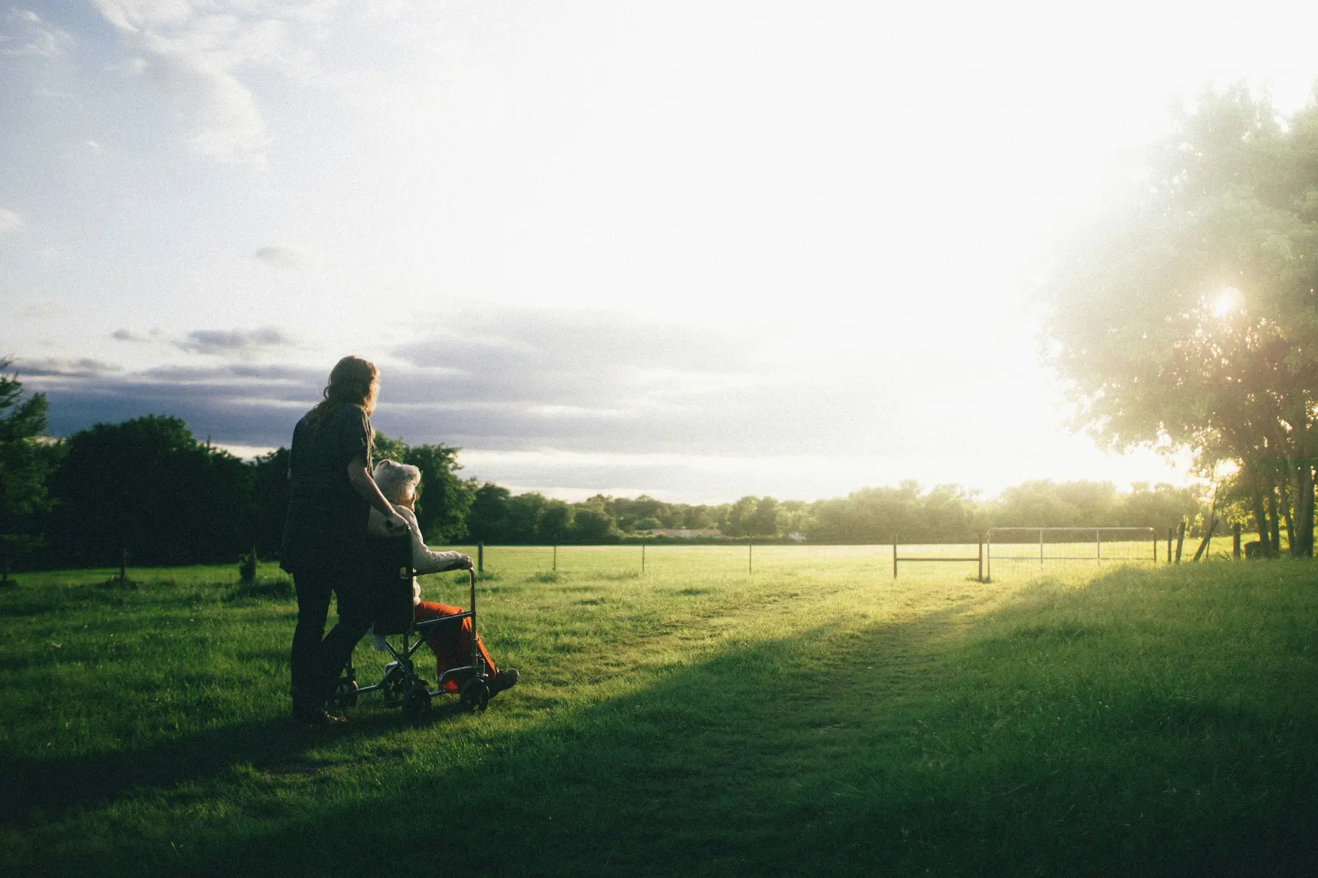 Carer pushing a wheelchair at golden hour